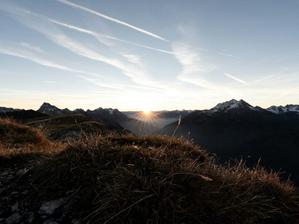 the sun is setting over a mountain range