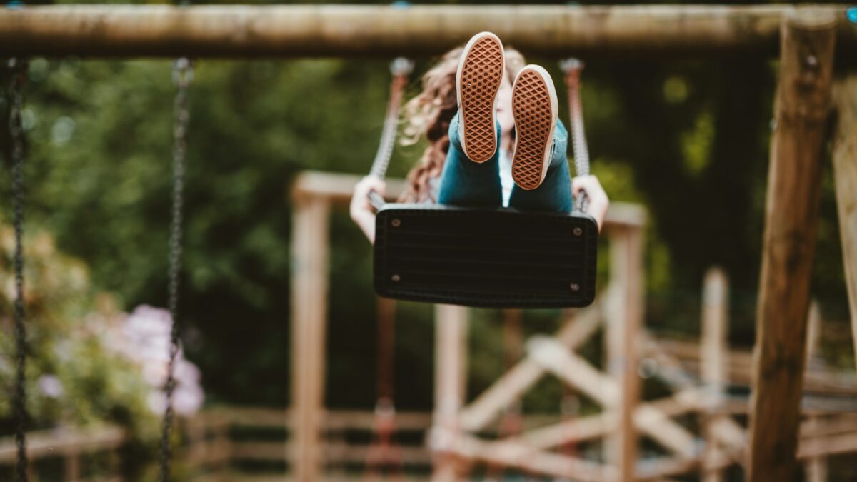 woman riding swing near trees