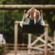 woman riding swing near trees