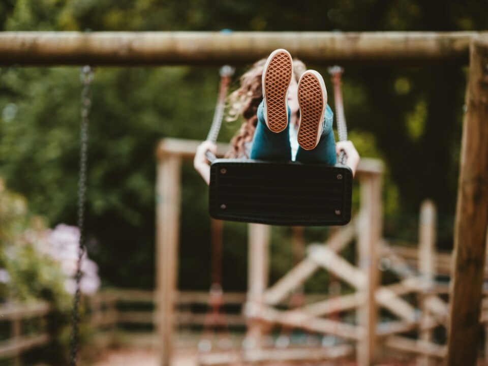 woman riding swing near trees