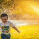 a young boy running through a sprinkle of water