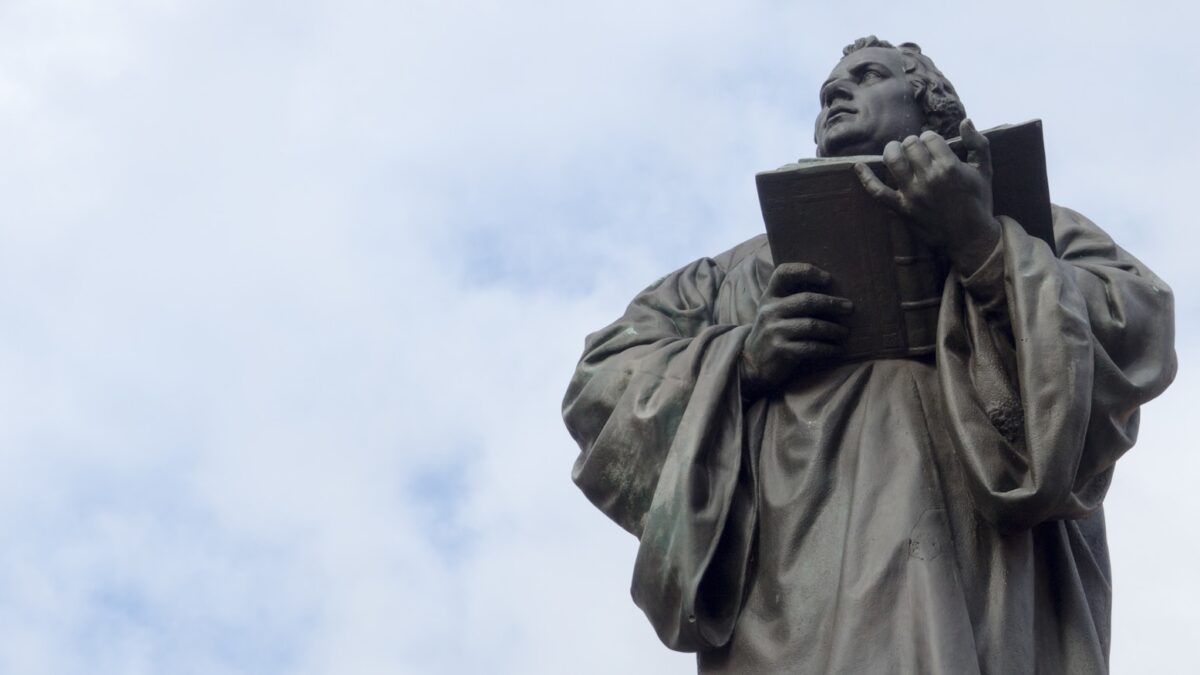 man holding book statue under white clouds during daytime