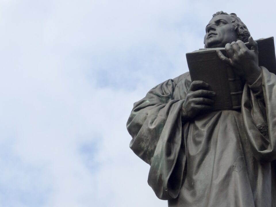 man holding book statue under white clouds during daytime