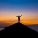 silhouette of person standing on rock during sunset