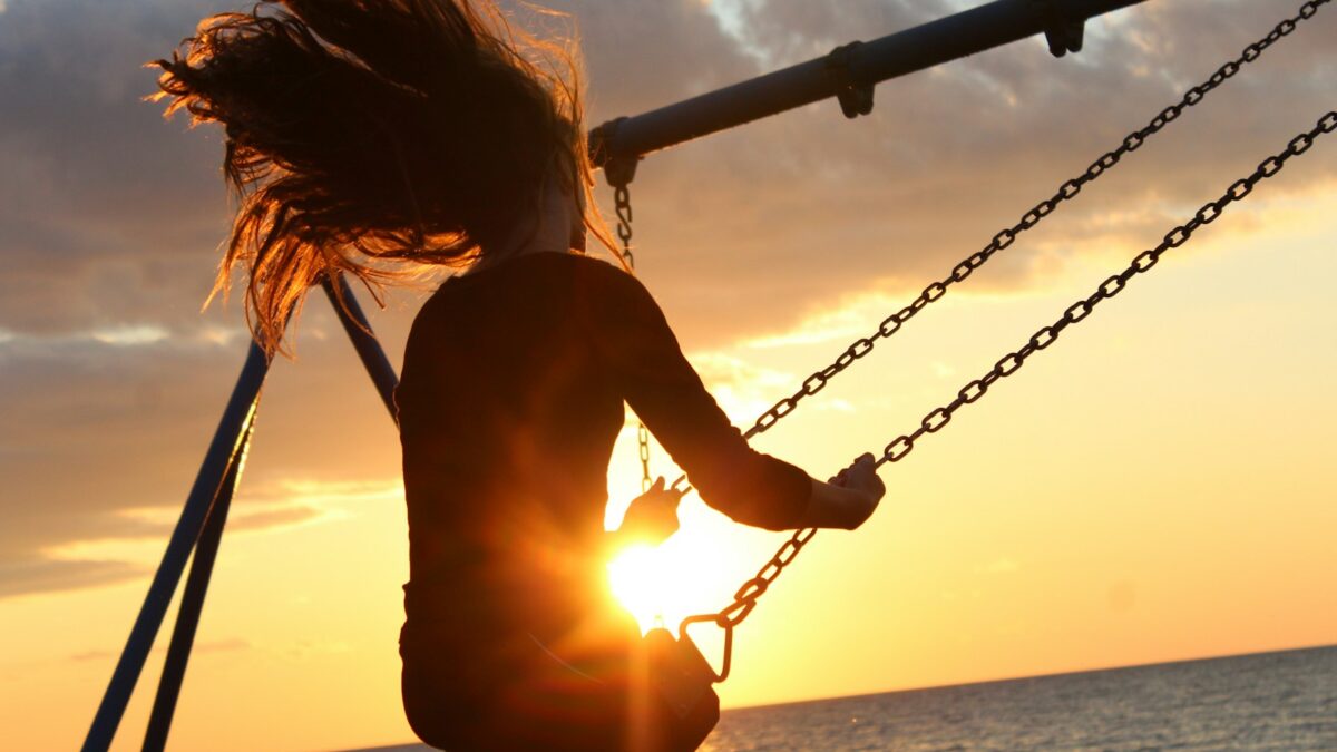 woman riding on swing during sunset