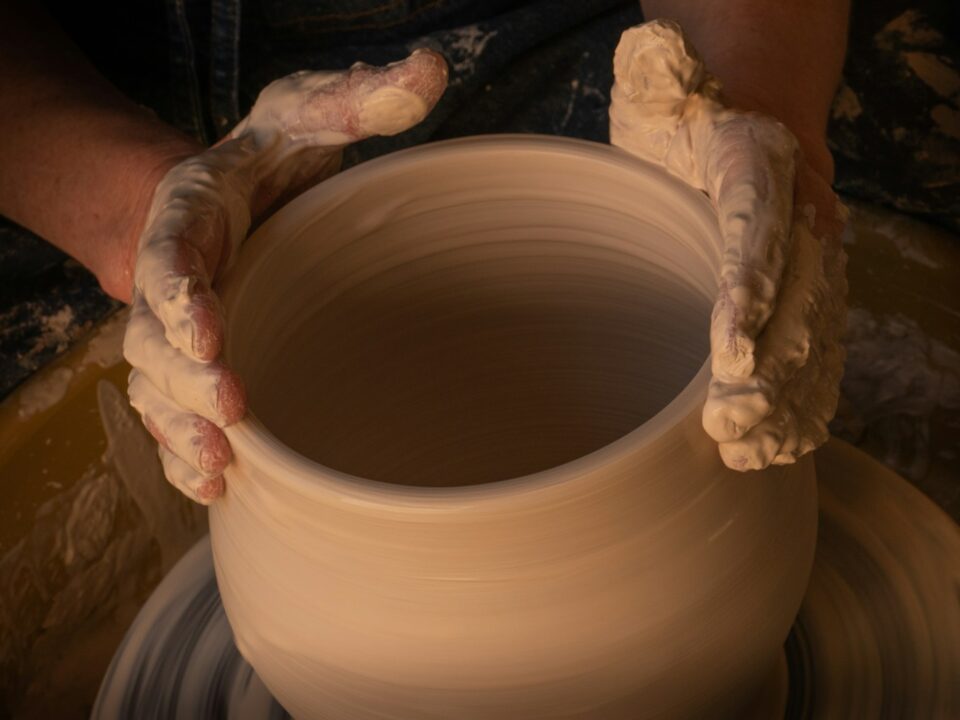 person holding white clay pot