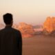 a man standing in front of a desert landscape