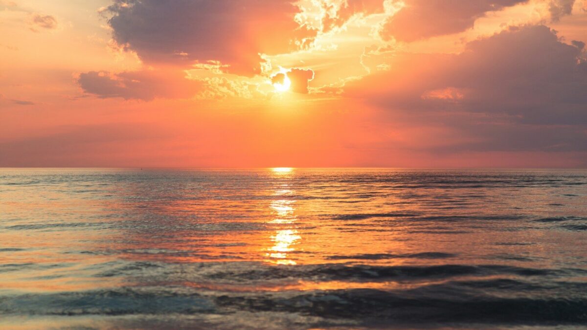 sea under white clouds at golden hour