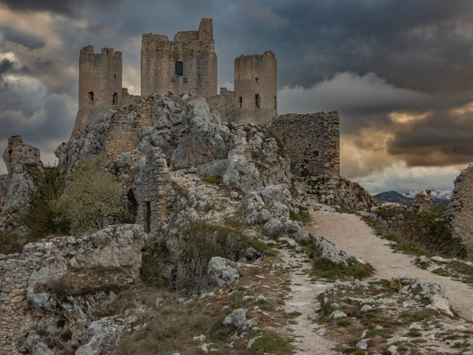 a stone castle on a rocky hill under a cloudy sky