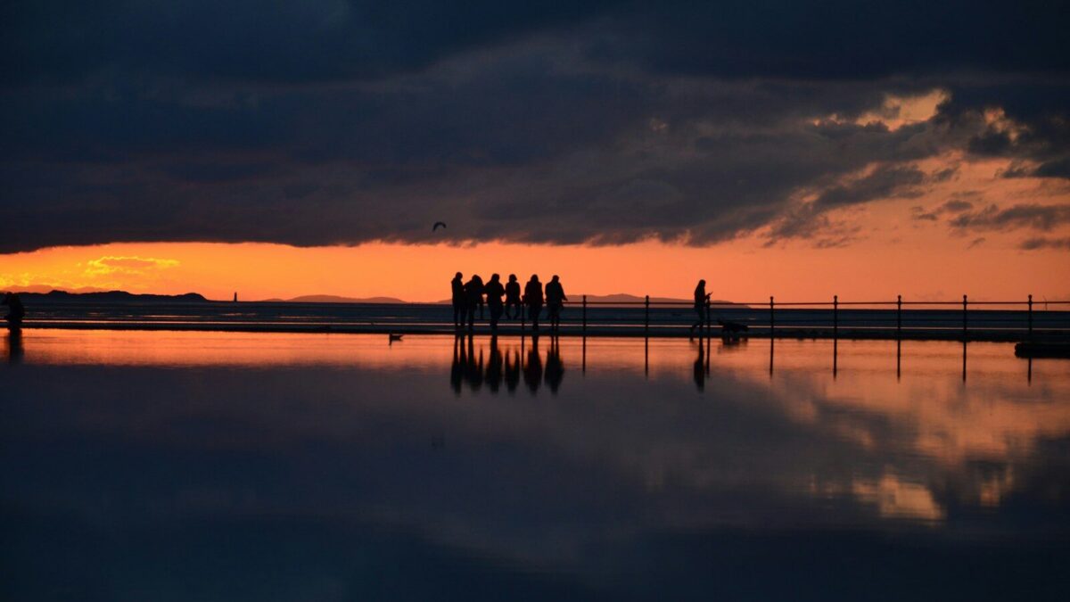silhouette of people standing on dock during sunset