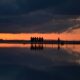silhouette of people standing on dock during sunset