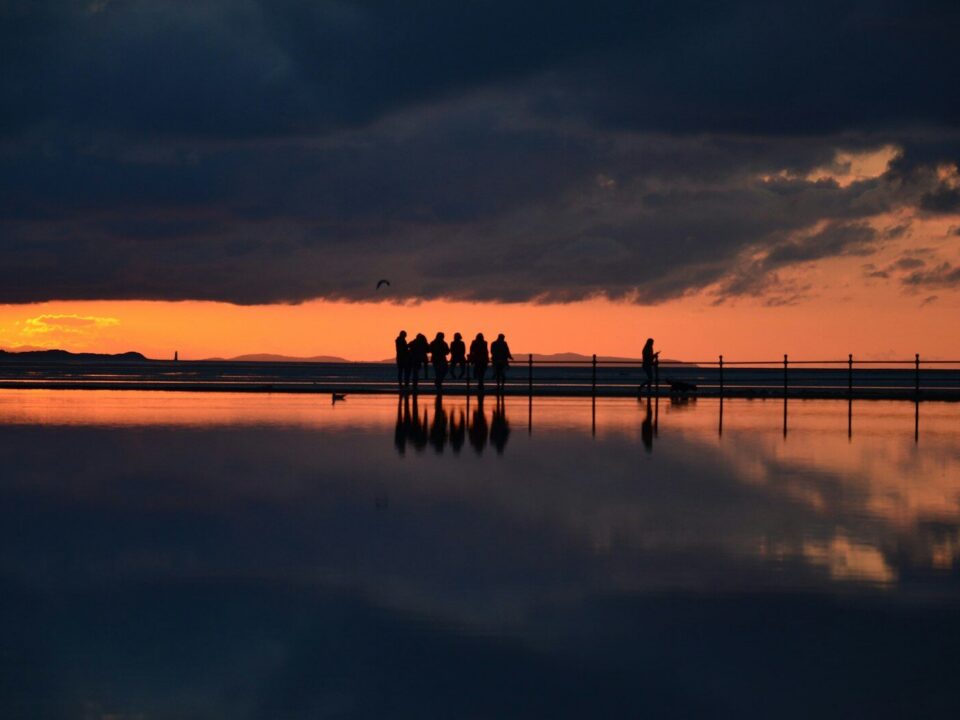 silhouette of people standing on dock during sunset