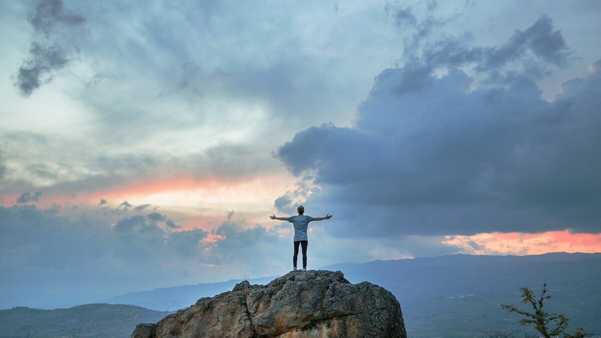 man standing on top of rock mountain during golden hour