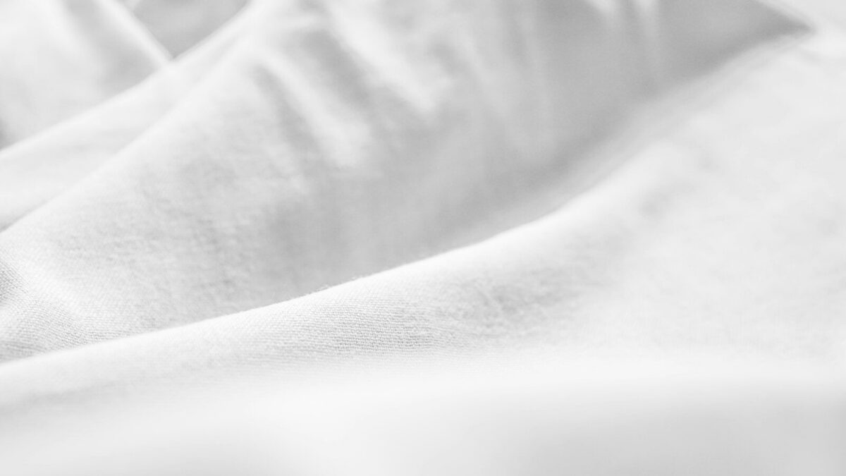 a black and white photo of a bed with white sheets