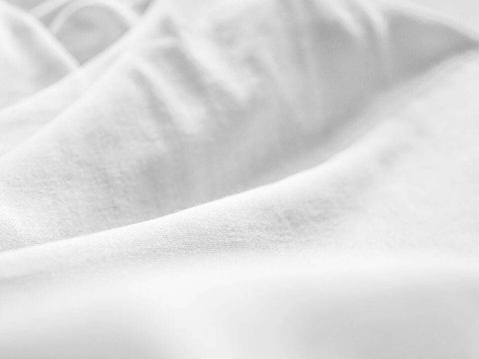 a black and white photo of a bed with white sheets