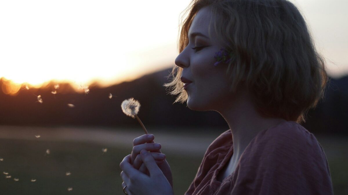 woman blowing dandelion flower selective focus photography