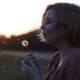 woman blowing dandelion flower selective focus photography