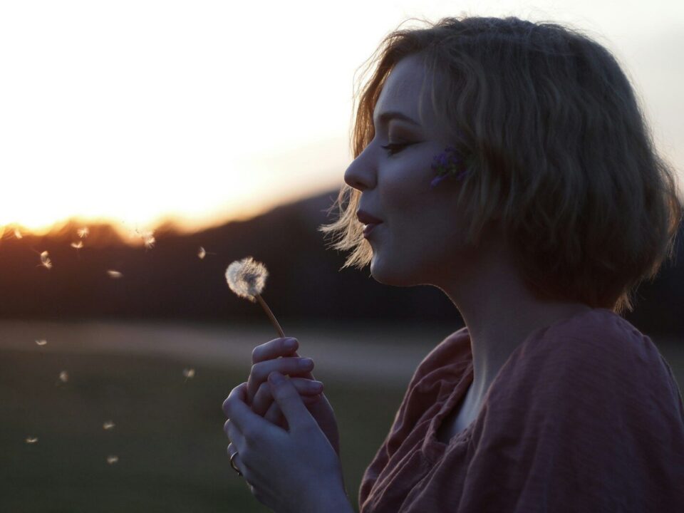 woman blowing dandelion flower selective focus photography