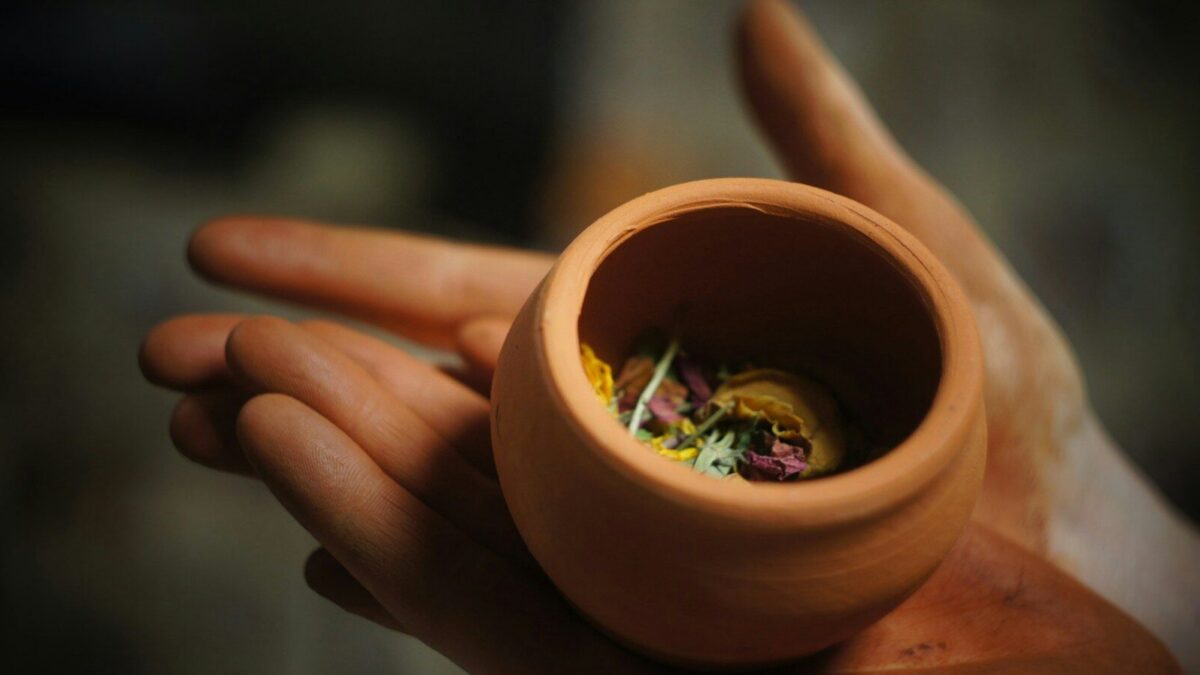 round brown clay pot on person's plams