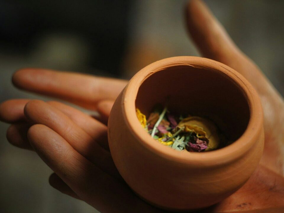 round brown clay pot on person's plams