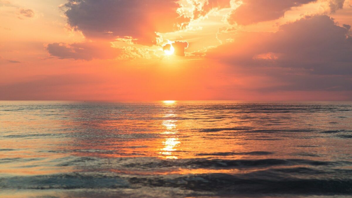 sea under white clouds at golden hour